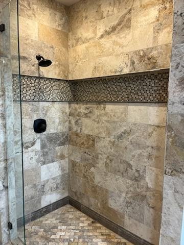 Walk-in shower with stone tile and mosaic accent band